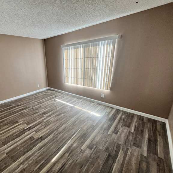 a room with wooden flooring and a window with blinds.