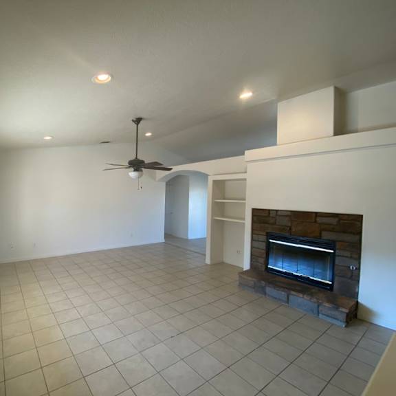 a living room with a fireplace and a ceiling fan.