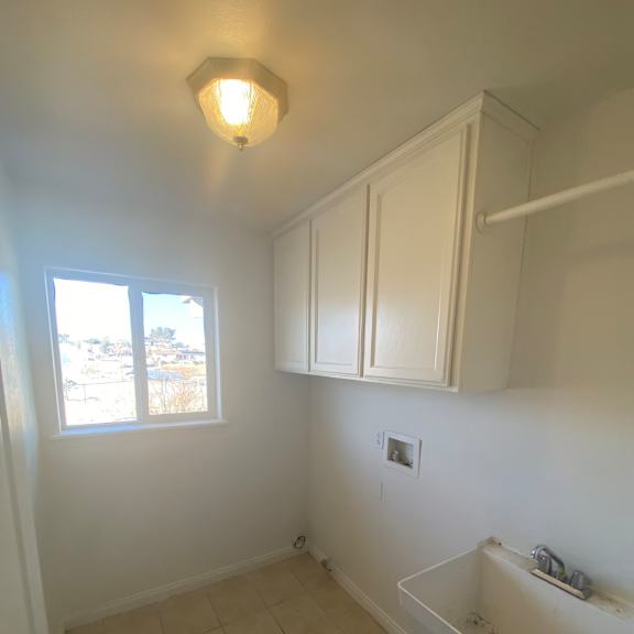 a bathroom with a window and a light on the wall.