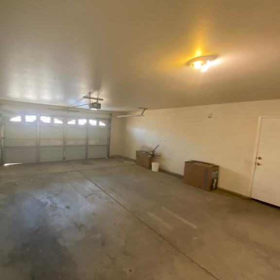 a large empty room with a white door and a window with blinds.
