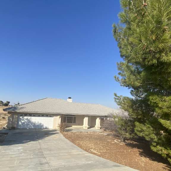 a house with a driveway and trees in the foreground.