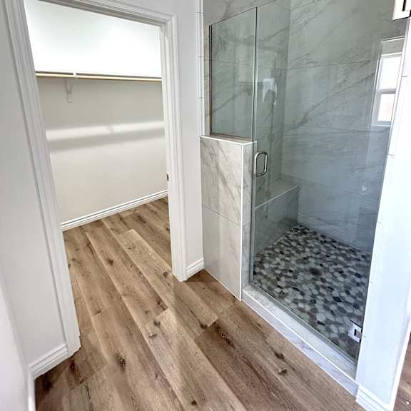 a bathroom with a walk-in shower and wooden floors.