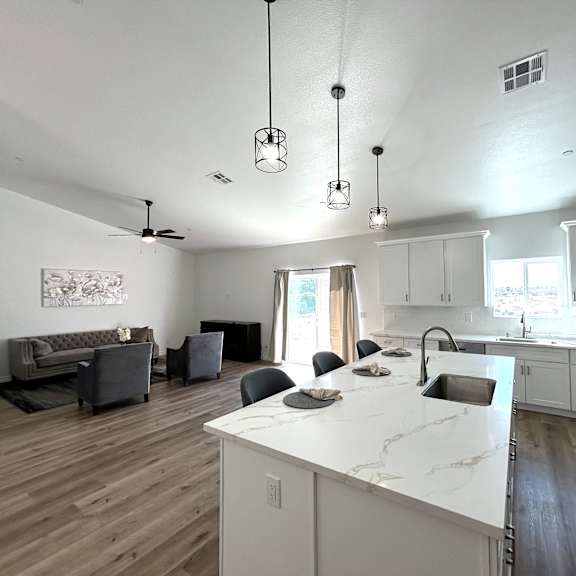 a kitchen with a white countertop and a dining area with a grey couch.