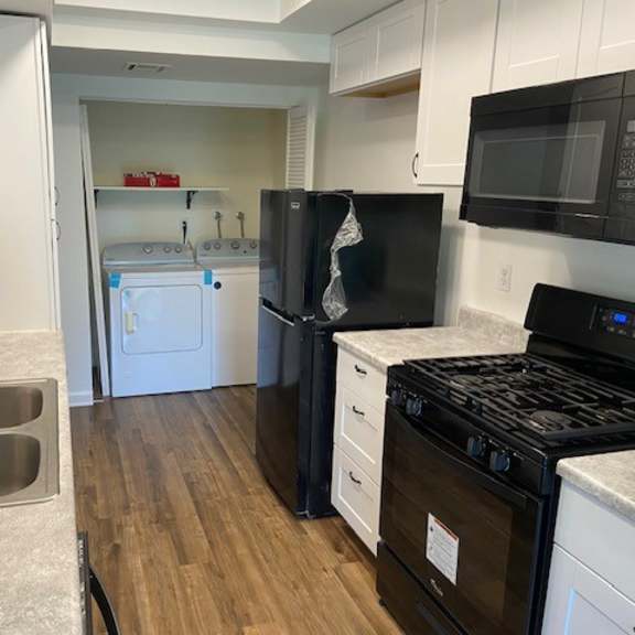 a kitchen with a black stove top oven and a black microwave above it.