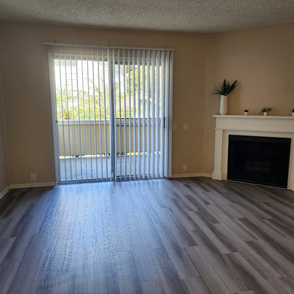 an empty living room with a fireplace and a sliding glass door