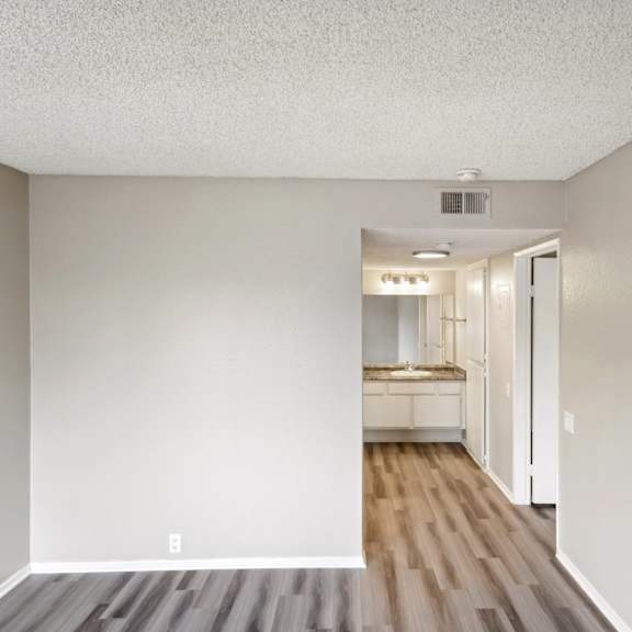 the living room of an apartment with wooden floors and white walls