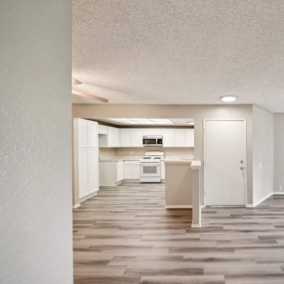 an empty living room and kitchen with wood flooring