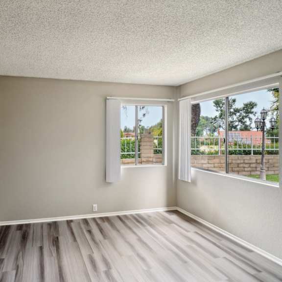 an empty living room with a large window and wooden floors