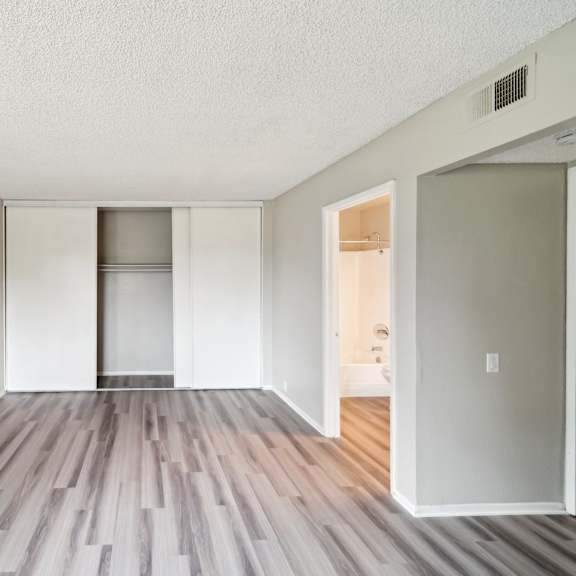 the spacious living room of an apartment with wood flooring