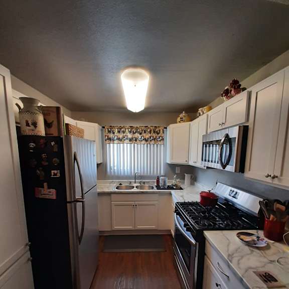 a small kitchen with white cabinets and a black refrigerator