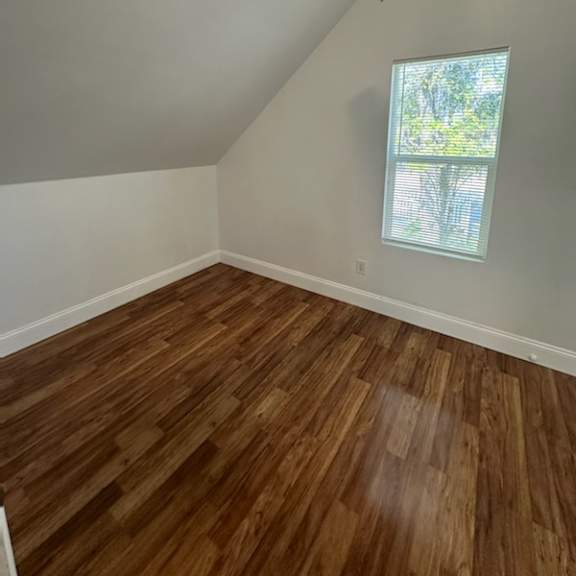 an empty room with wooden floors and a window
