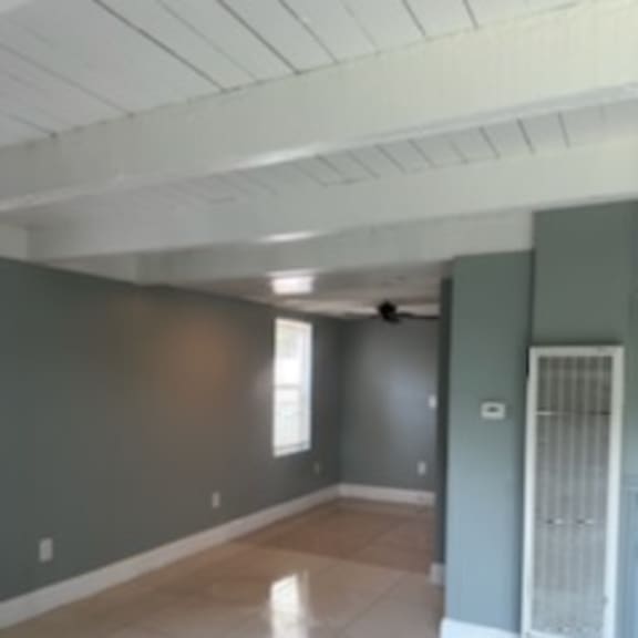 an empty living room with a white tile floor and green walls