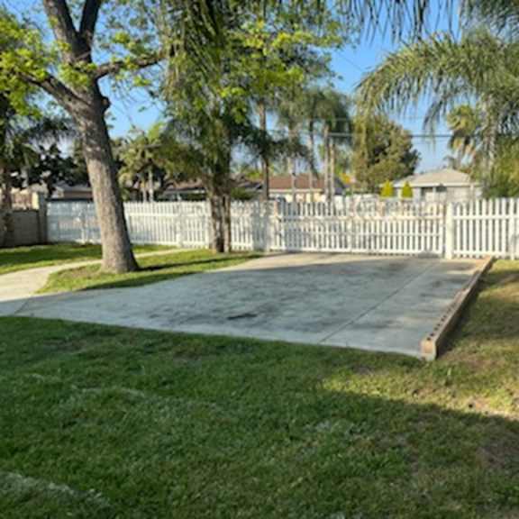 a sidewalk in a yard next to a white fence