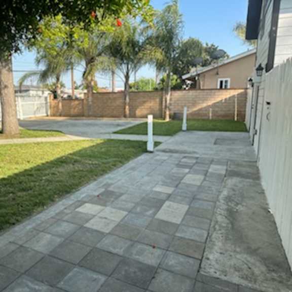a sidewalk in front of a house with a fence
