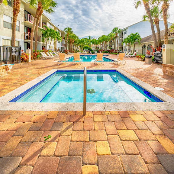 a resort style pool with palm trees and buildings in the background