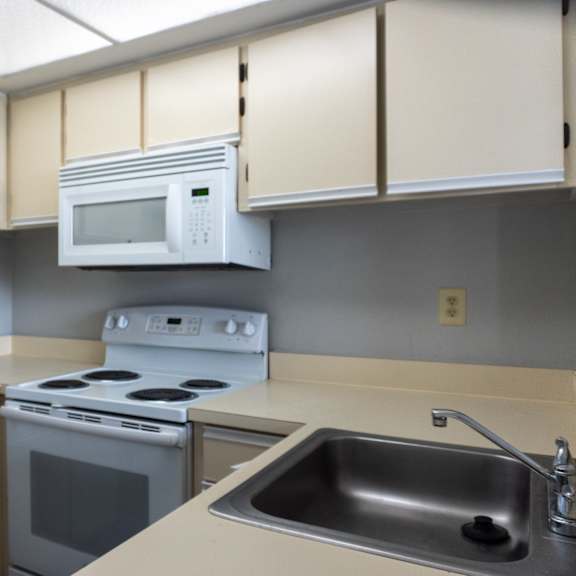 an empty kitchen with a stove microwave and sink at bella lago vista, west palm beach, florida