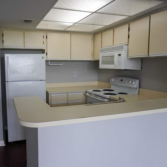 an empty kitchen with white cabinets and a refrigerator at bella lago vista, west palm beach