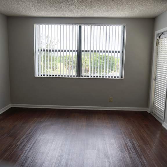 an empty living room with wood floors and a large window at bella lago vista, west palm beach