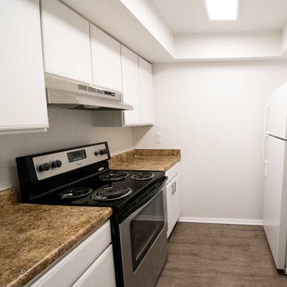 a kitchen with white cabinets and stainless steel appliances and granite counter tops at red bay apartment complex, jacksonville, fl