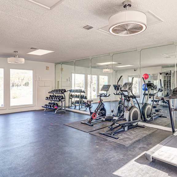 a fitness room with cardio equipment and mirrors at red bay apartment complex, jacksonville, fl