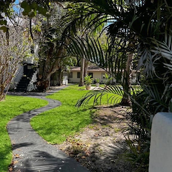 a pathway in a garden with a white fence on the right.