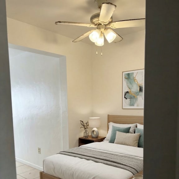 a bedroom with a bed, nightstand, and a ceiling fan.