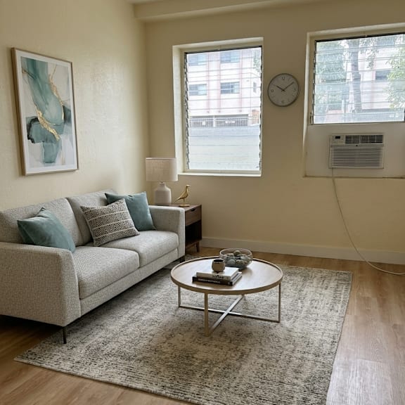 a living room with a couch, a coffee table, a rug, a clock, and a painting on the wall.
