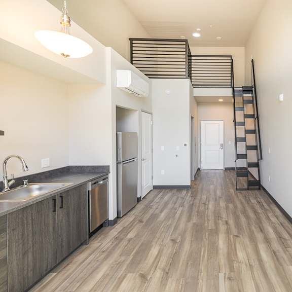 a kitchen with a stainless steel sink and a staircase on the wall