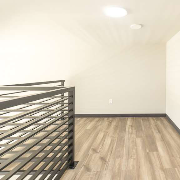 a bedroom with white walls and wood floors and a metal bed