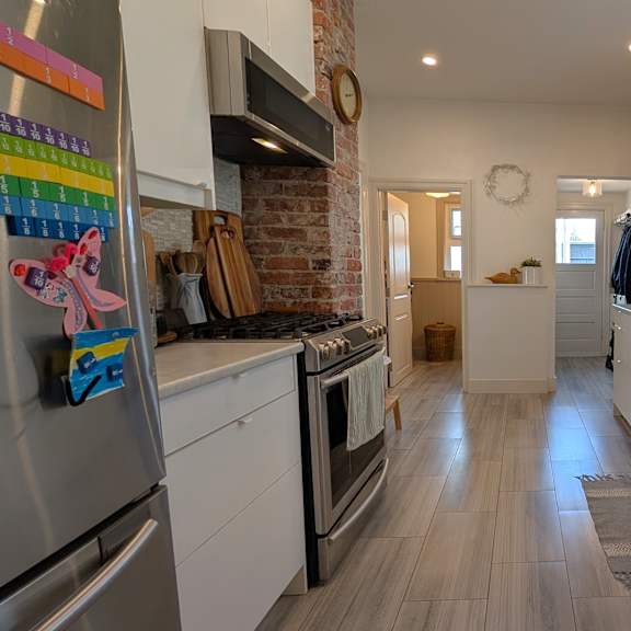 a kitchen with white cabinets and a brick wall.