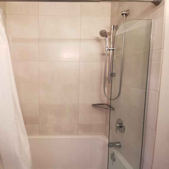 a white shower curtain hangs over a white bathtub in a bathroom.