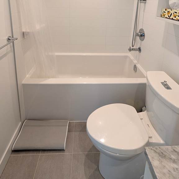 a white toilet sits in a bathroom next to a bathtub.