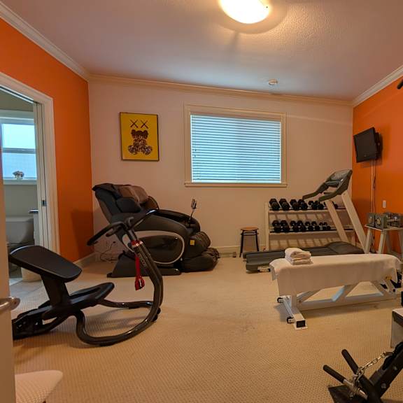 a home gym with orange walls and a variety of exercise equipment.