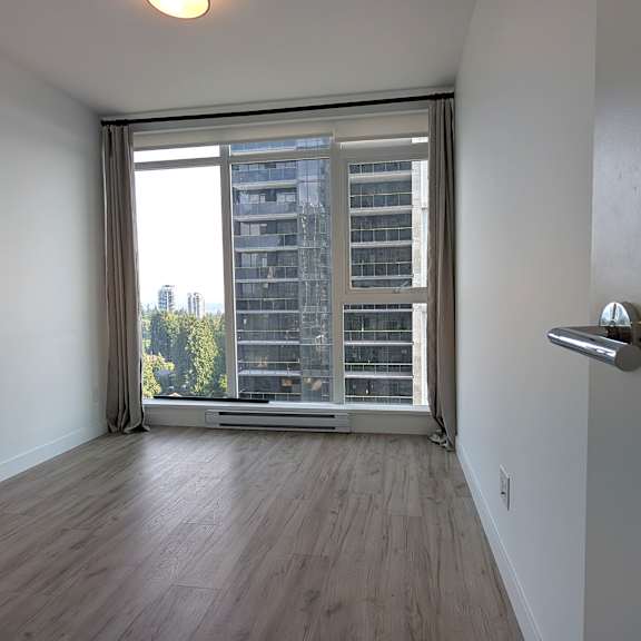 a room with a wooden floor and a large window overlooking a building.