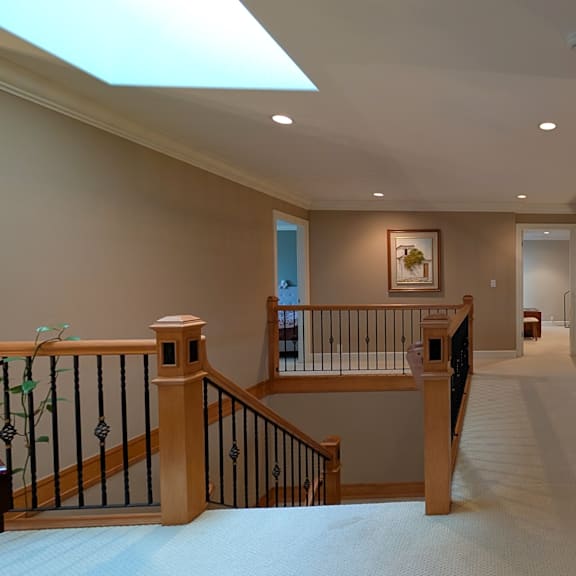 a hallway with a skylight and a painting on the wall.