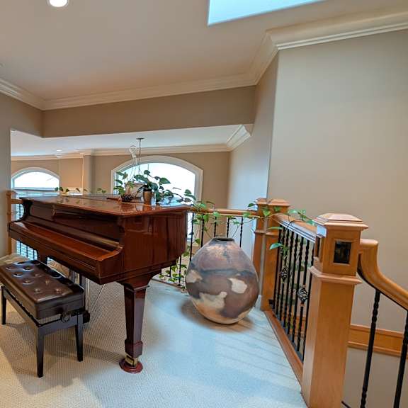 a grand piano sits in a spacious room with a bench in front of it.