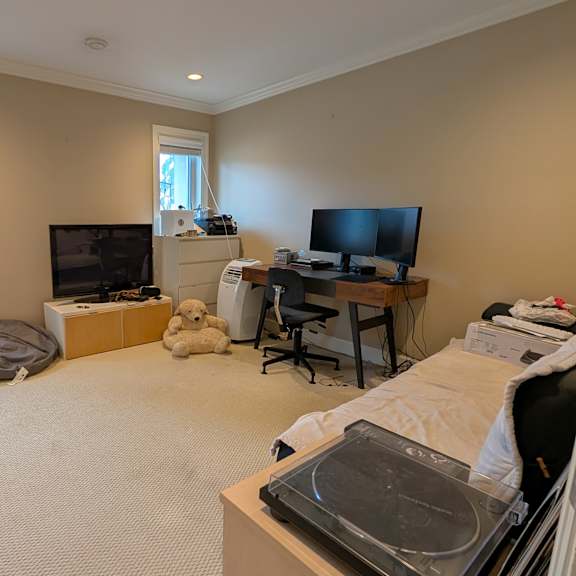 a room with a bed, a desk, a chair, a television, and a window.