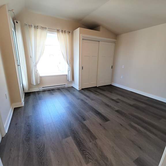 a room with wooden floors and a window with curtains.