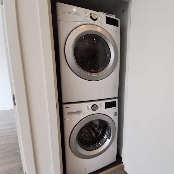 two washing machines are stacked in a small space.
