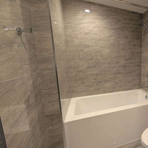 a modern bathroom with a white tub, toilet, and sink.