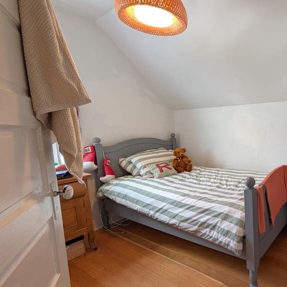 a small bedroom with a bed, dresser, and a striped bedspread.