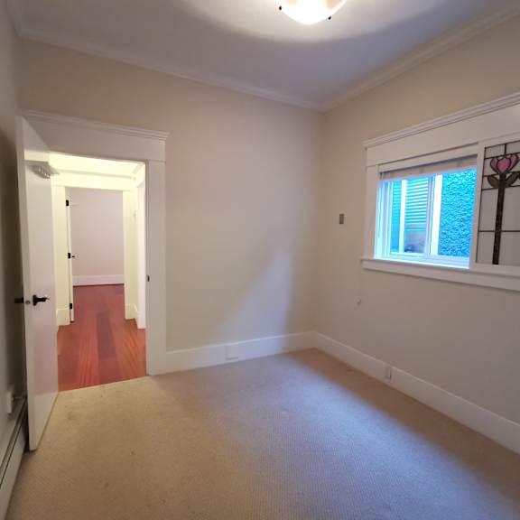 a room with a carpeted floor and a window with a pink decoration on it.