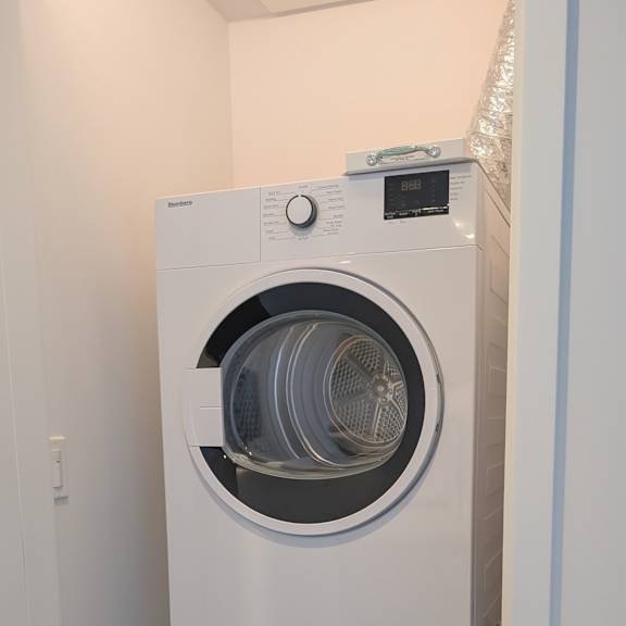 a white front load washing machine in a laundry room.