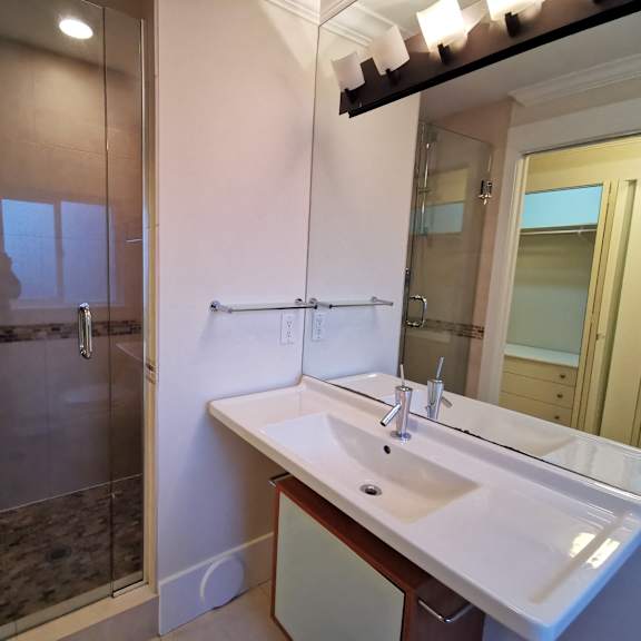 a bathroom with a walk-in shower, double sink vanity, and a large mirror.