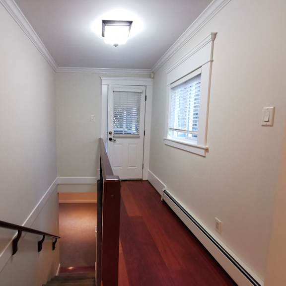 a hallway with a wooden floor and white walls.