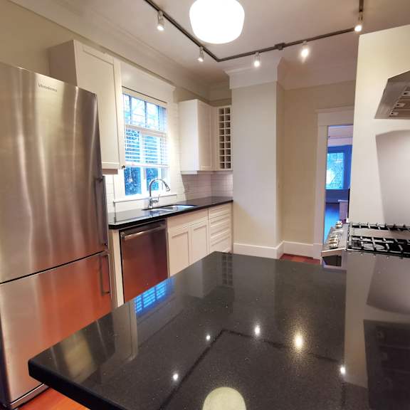 a kitchen with a black counter top and stainless steel appliances.