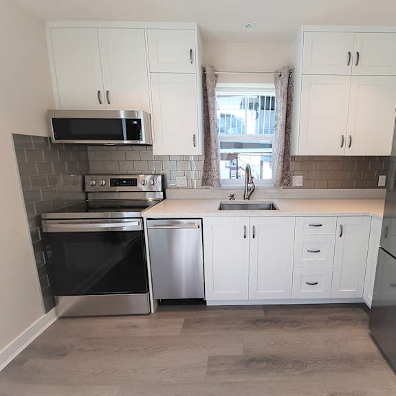 a kitchen with white cabinets and stainless steel appliances.