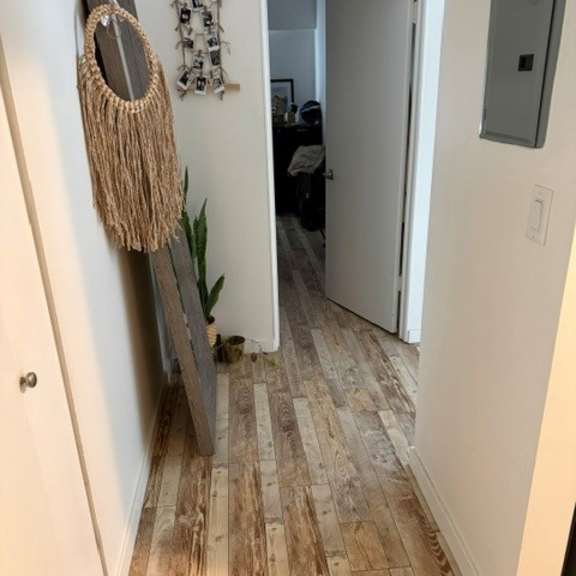 a hallway with a wooden floor and a mirror hanging on the wall.