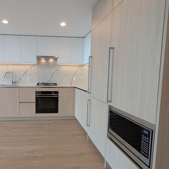 a modern kitchen with wooden floors and white cabinets.