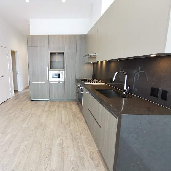 a modern kitchen with a wooden floor and a dark counter.